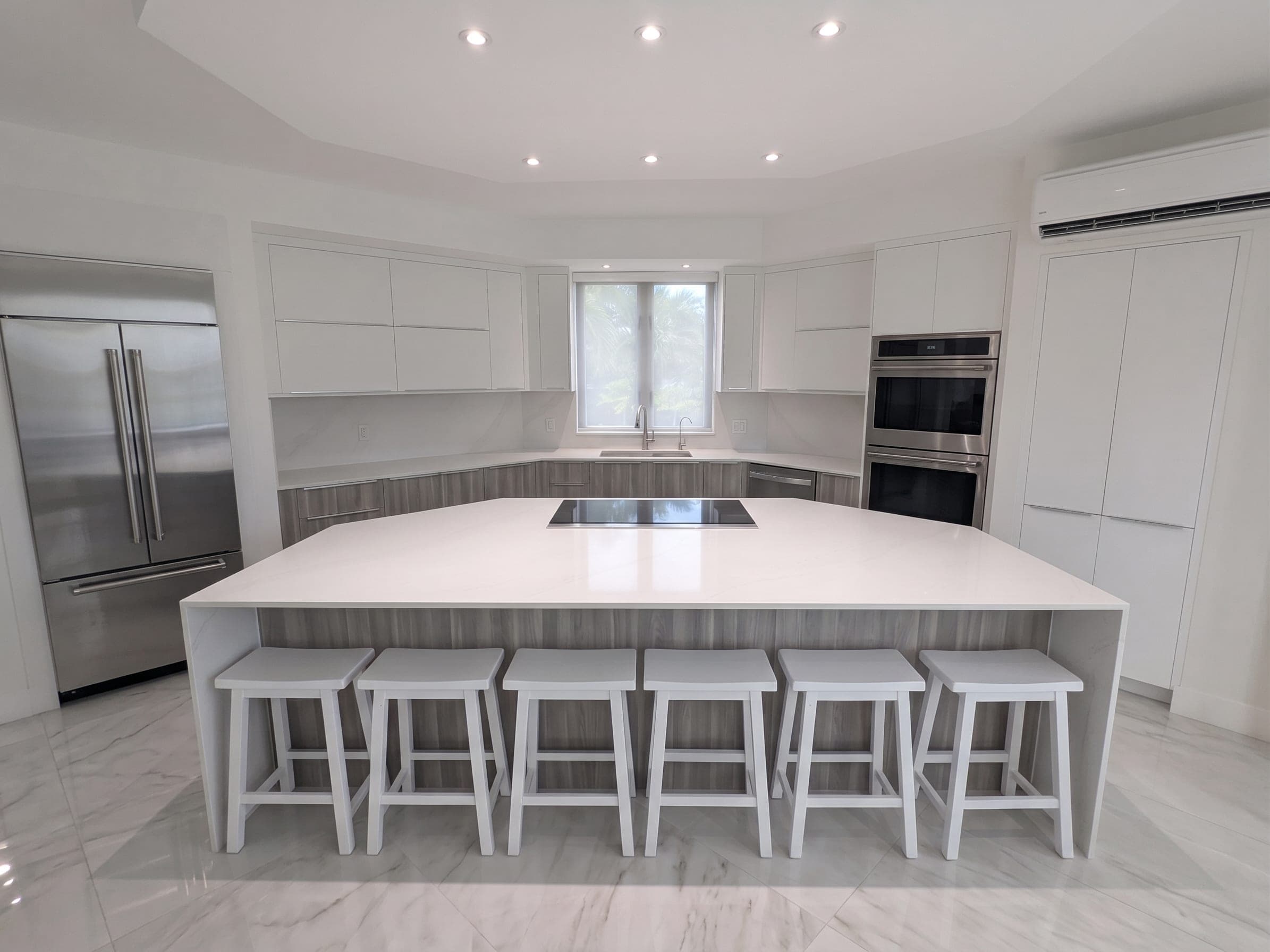 Kitchen island with waterfall quartz countertops and seating for six, induction cooktop, and double wall ovens