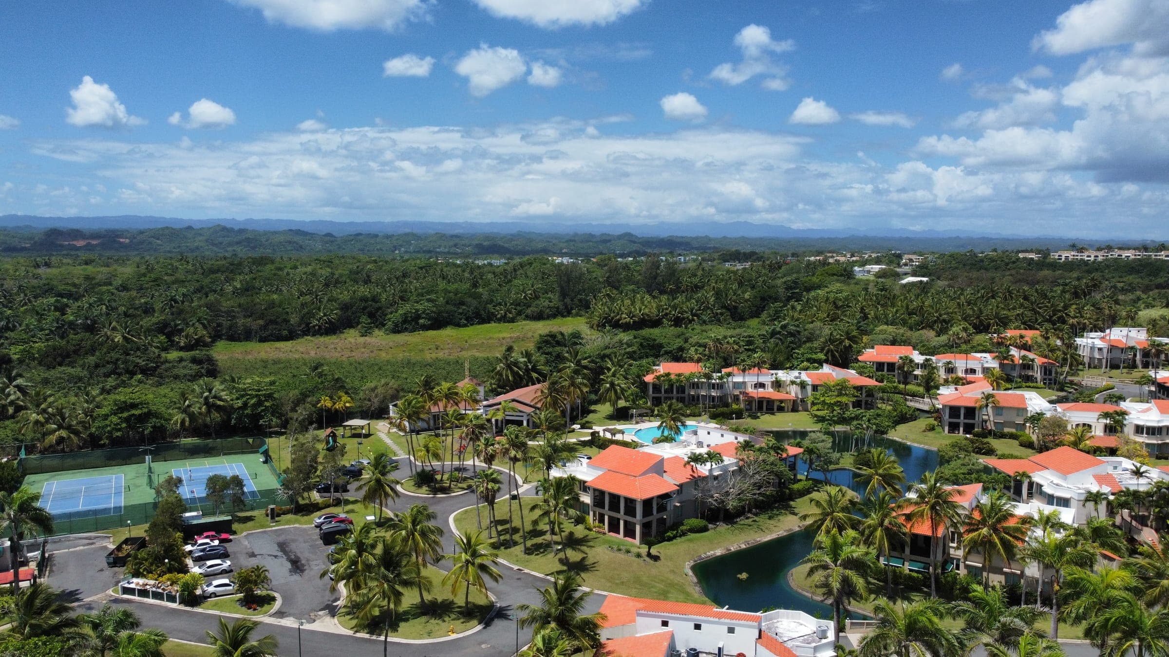 Aerial view of Lakeside Villas community showing the pool, tennis courts, lakes, and surrounding mountains