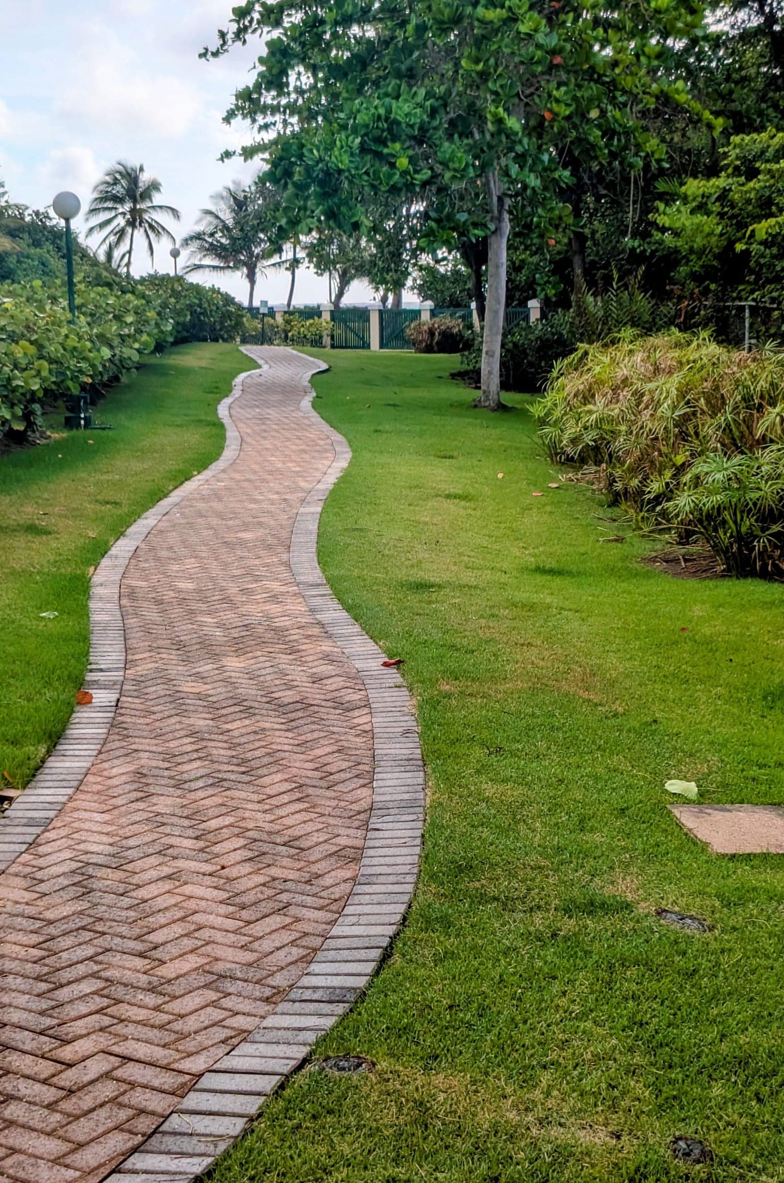 Brick pathway through manicured grounds with the ocean visible in the distance