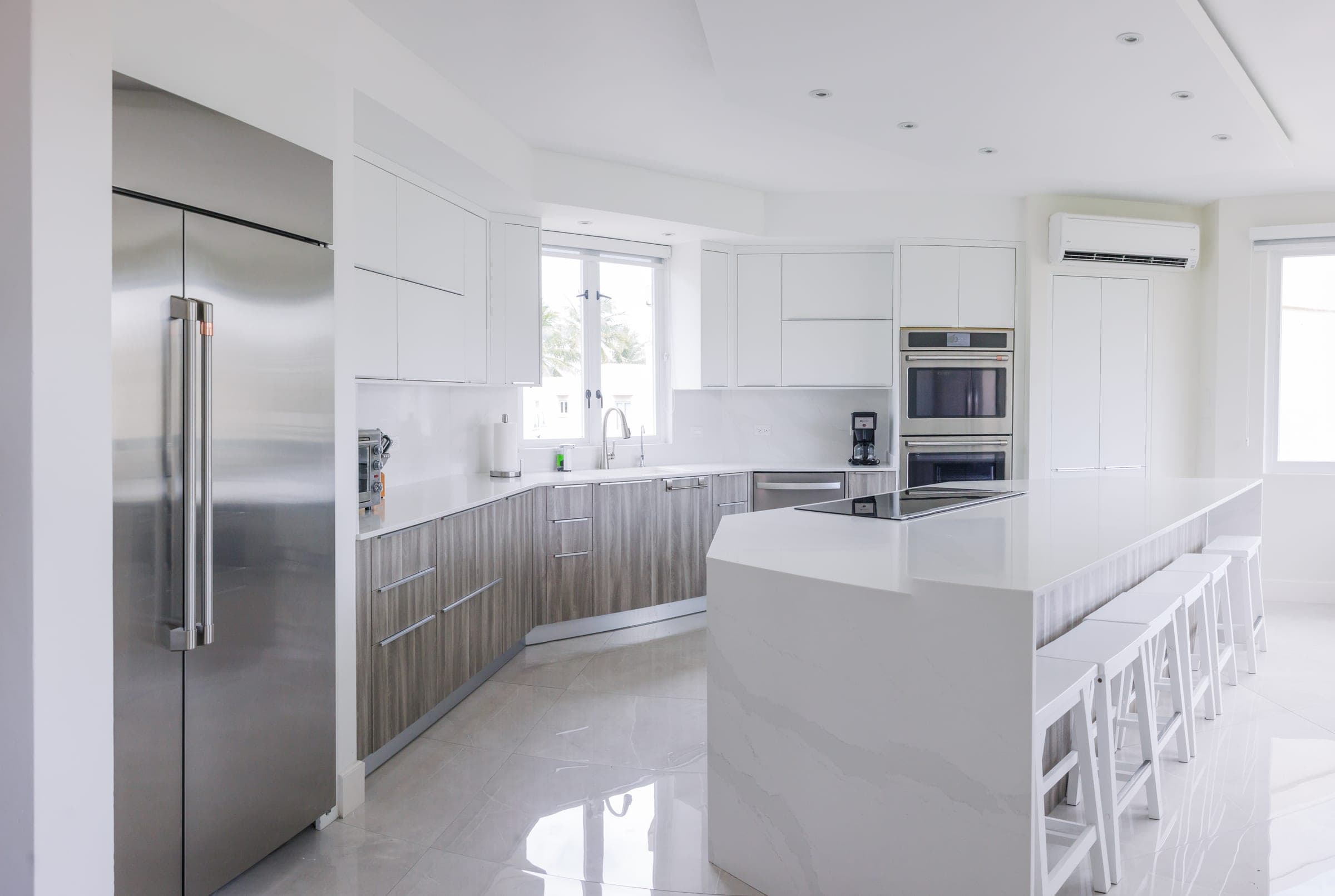 Renovated kitchen with waterfall quartz island, panel-integrated refrigeration, double wall ovens, and induction cooktop